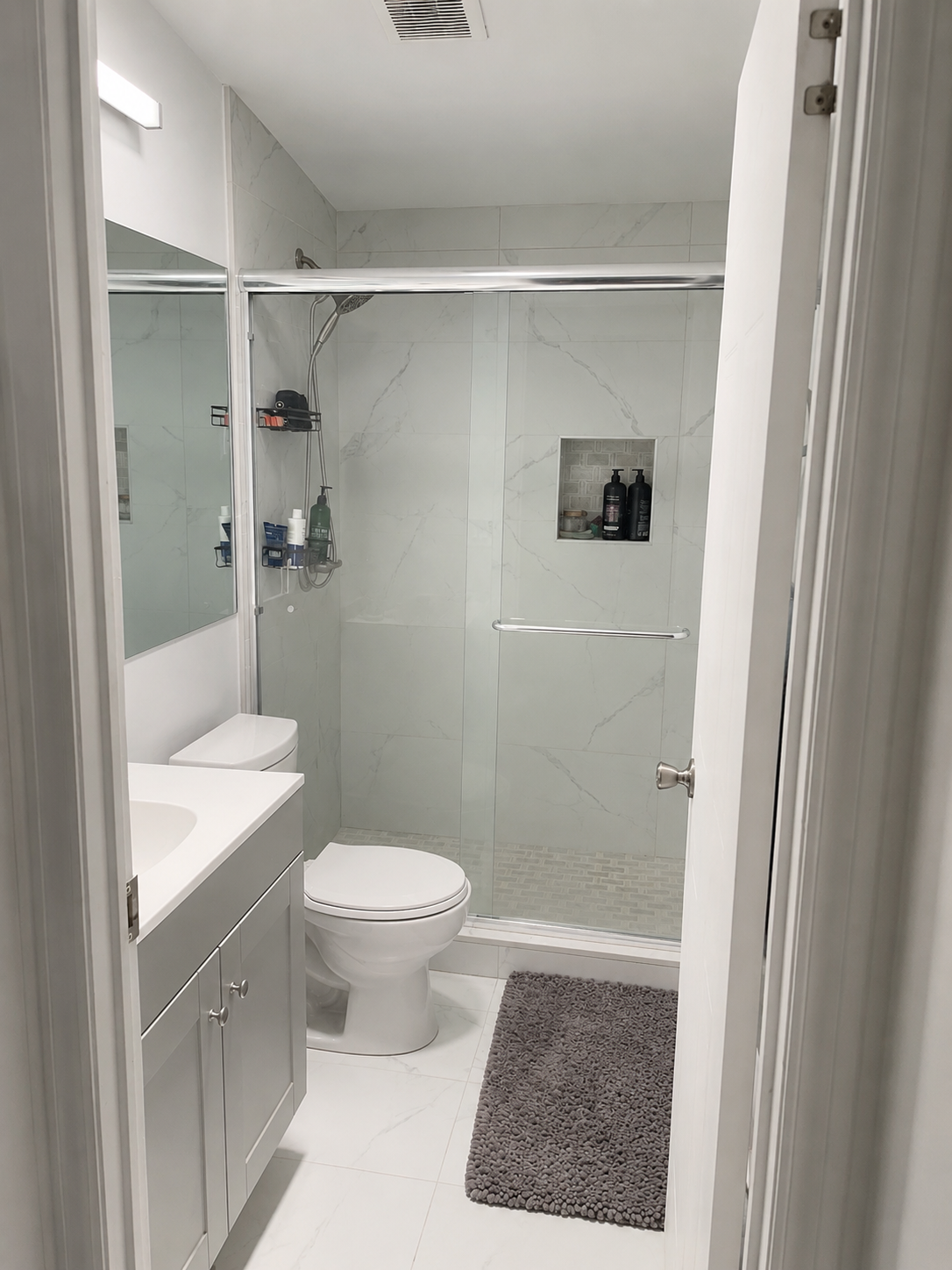 Renovated bathroom with glass shower and marble tile